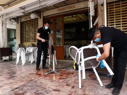 Dos empleados de una cafetería de Málaga preparan el lunes la terraza para poder abrir al público.
