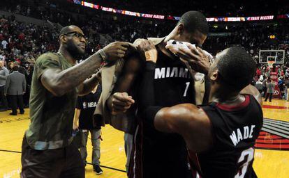 LeBron James, vestido de calle, y Wade celebran con Bosh su triple decisivo.
