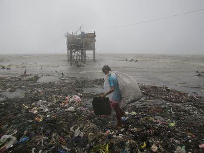 Un hombre busca entre los restos dejados tras el paso del tifón Koppu, en Navotas, al norte de Manila, este domingo.