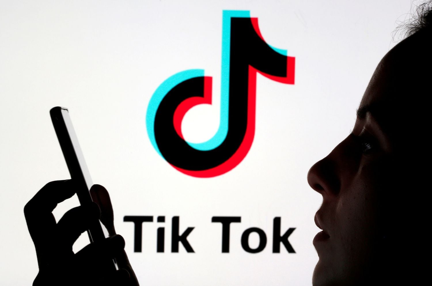 Una persona sostiene un teléfono móvil ante el logotipo de la red social china Tik Tok.