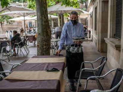 Un camarero recoge una mesa en la terraza de su restaurante, en Orense.