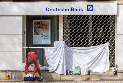 Una persona sin hogar recoge sus pertenencias tras haber pasado la noche en la puerta de una entidad bancaria en pleno centro de Sevilla.