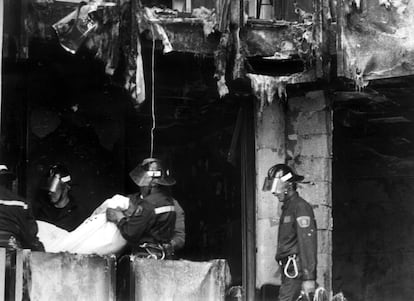 Los bomberos trasladan uno de los cadáveres de las víctimas del incendio registrado en una vivienda de Móstoles (Madrid), cuya fachada estaba recubierta de material inflamable, en el que murieron 12 personas.