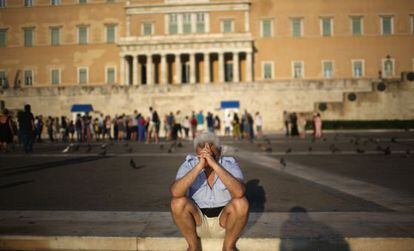 Un ciudadano se sienta pensativo frente al Parlamento griego.