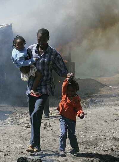 Un hombre y sus hijos entre los incendios en un suburbio de Nairobi.
