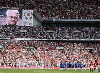 Los jugadores de Manchester y Chelsea rinden homenaje antes del partido a Bobby Robson, cuyo rostro aparece en el electrónico.