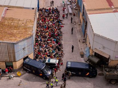 Menores extranjeros no acompañados, a las puertas de una nave usada como albergue provisional en Ceuta, el miércoles.