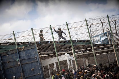 A Moroccan riot police officer points a missile at sub-Saharan migrants on the fence that separates Moroccan and Spanish territory in Melilla.  