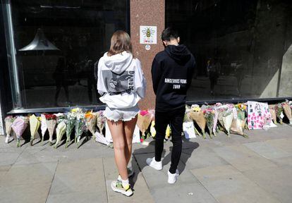 Dos jóvenes con sudaderas de Ariana Grande dejan flores en la plaza de Santa Ana en Manchester, en el primer aniversario del atentado en el Manchester Arena. 