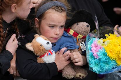 Una niña sostenía un peluche del oso Paddington y otro de un corgi mientras espera para ver el ataúd de la procesión fúnebre, el lunes en Edimburgo (Escocia).