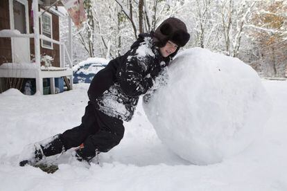 Un ni&ntilde;o empuja una gigantesca bola de nieve en el jard&iacute;n de su casa en Townshend, en Vermont, EE.UU.