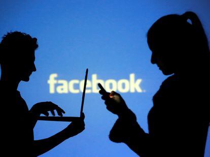 Dos personas, frente al logo de Facebook.