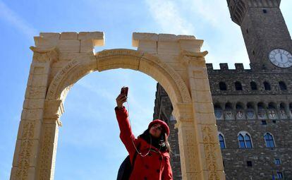 Una turista se fotograf&iacute;a con una r&eacute;plica del arco del triunfo de Palmira en la plaza de las Se&ntilde;or&iacute;as en Florencia.