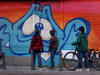 Tres niños del barrio observan una de las pintadas en la calle Corredera Alta de San Pablo.