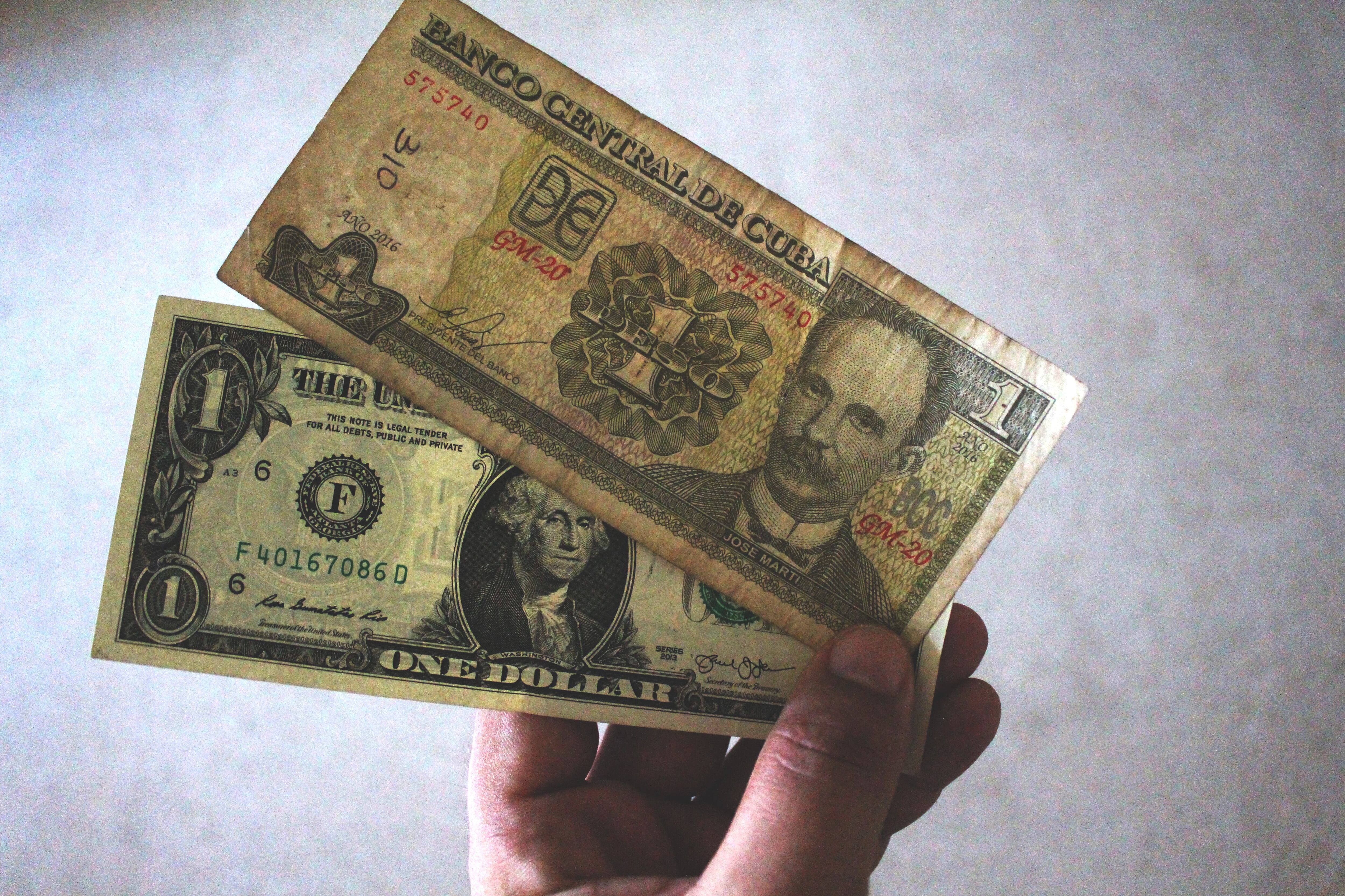 Un billete de un peso cubano con la imagen de José Martí sobre otro de un dólar con la imagen de George Washington.