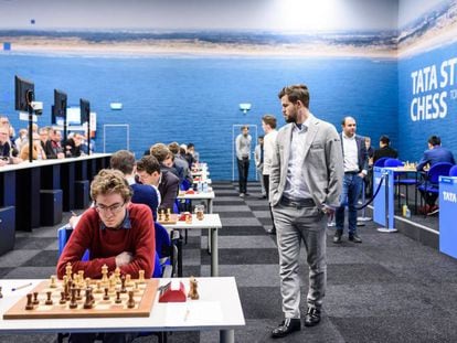 Magnus Carlsen pasea por la sala de juego en Wijk aan Zee durante su partida de este lunes; en primer plano, el español David Antón, participante en el Torneo B