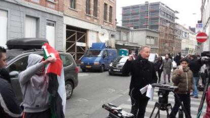 Momento en que un hombre saca una bandera palestina durante una retransmisión televisiva frente a la casa de Abdeslam.