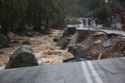 Varias personas caminan por una carretera colapsada por las inundaciones en Volos (Grecia).
