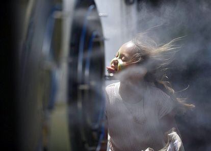 Una niña se refresca junto a un ventilador nebulizador en el Abierto de Australia que se celebra en la ciudad de Melbourne (Australia).
