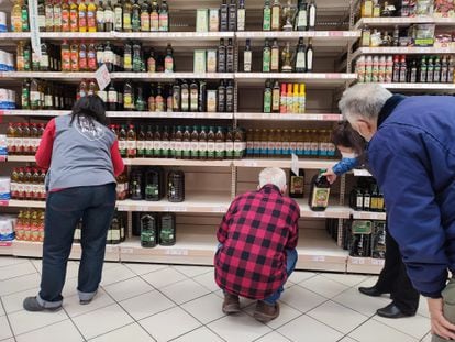Varias personas compran aceite en un supermercado de Madrid, donde algunas estanterías permanecen vacías a causa de la huelga indefinida de transporte.
