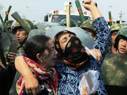 Mujeres de la minoría uigur rodeadas por policías chinos en Urumqi, durante los disturbios de julio de 2019.