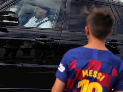 Un niño con la camiseta de Messi, ante el coche de Luis Suárez.