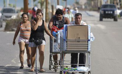 Dos hombres llevan en un carrito los productos que han sacado de un centro comercial en Los Cabos.