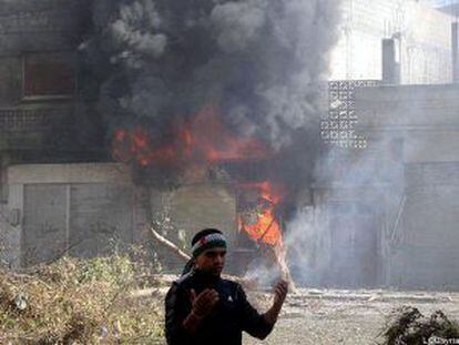 Un hombre junto a una casa en llamas bombardeada por el ej&eacute;rcito Sirio en la ciudad de Homs el 12 de febrero.