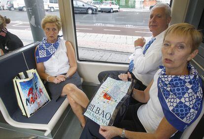 Varias personas portan algunos de los articulos promocionales, ayer en el tranvía de Bilbao.