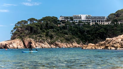 Una mujer practica paddle surf en la playa de Aiguablava, en Begur (Girona), con el parador homónimo al fondo.