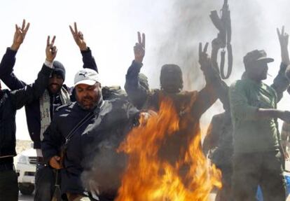 Milicianos rebeldes gritan en torno a una hoguera hecha con uniformes de soldados libios en la carretera entre Bengasi y Ajdabiya.