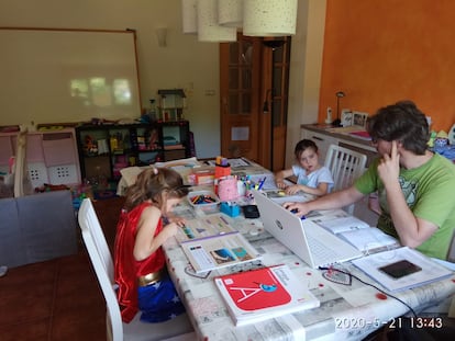 El profesor del IES Vega de Toranzo, Pablo Blanco, con sus hijas, en su salón, convertido en aula para la cuarentena.