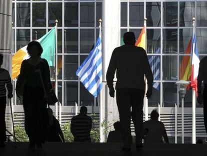 Viandantes en las escaleras del Parlamento Europeo en Bruselas donde ondean las banderas de la UE.