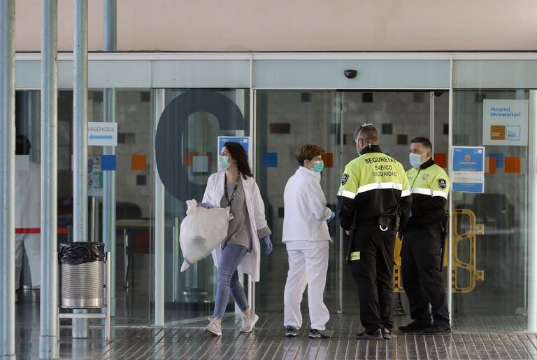 Dos agentes de seguridad junto a dos enfermeras en la entrada principal del Hospital del Mar de Barcelona. EFE / Andreu Dalmau