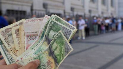 Una persona muestra varios billetes de las antiguas pesetas, mientras espera cola en junio de 2021 a las puertas del Banco de España para canjearlas.