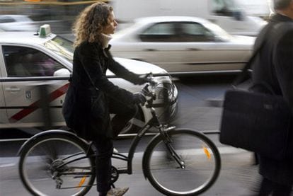 Una mujer circula en bicicleta por la acera de una calle de Madrid.
