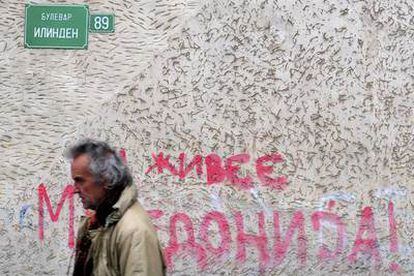 Un ciudadano de Eskopje camina ante una pintada con el lema 'larga vida a Macedonia'.