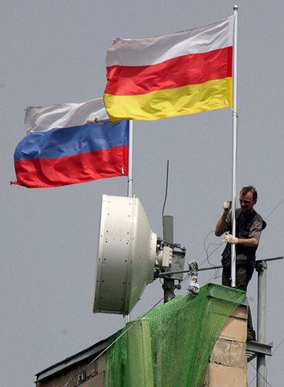 Un hombre arregla las banderas de Rusia y Osetia del Sur en un edificio en la capital, Tsjinvali.