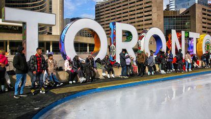 Varios jóvenes esperan en una pista de hielo instalada en el centro de Toronto.