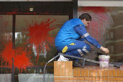 Un empleado municipal limpia las manchas de la pintura lanzada contra una sede del PNV en Vitoria.