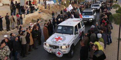Un grupo de sirios tras cruzar el paso fronterizo liban&eacute;s de Masnaa este lunes en un convoy de la Cruz Roja y la ONU.