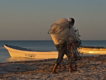 Un pescador carga sus redes mientras se prepara para salir a pescar desde un puerto en Yucatán (México).