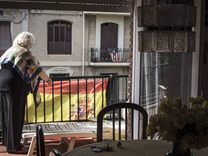 Una vecina coloca en su balc&oacute;n una bandera espa&ntilde;ola, frente a una casa con la estelada nacionalista catalana, en una calle de Barcelona.   