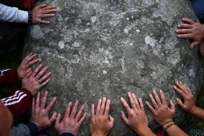 Varias personas tocan una de las rocas de Stonehenge en el solsticio de verano.