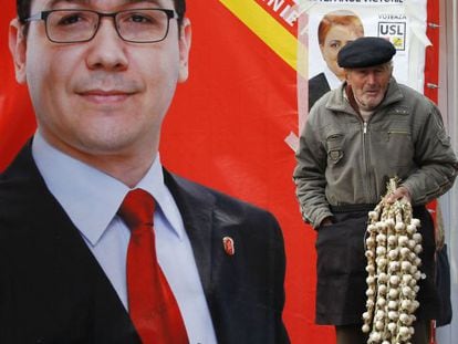 Un hombre vende ajos frente a un cartel del primer ministro Victor Ponta.