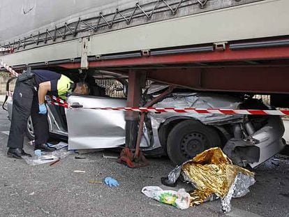 Un policía local de Leganés inspecciona el Seat Córdoba que se estrelló contra un remolque.