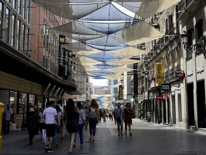 Varias personas pasean por la calle Preciados de Madrid, cubierta con toldos para tapar el sol.