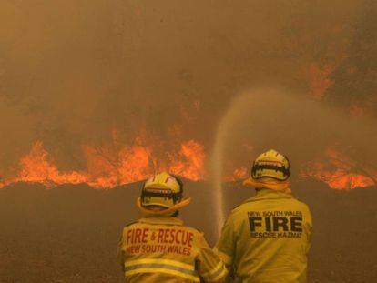 Dos bomberos trabajan este sábado en la extinción de un incendio forestal en Old Bar (Nueva Gales del Sur, Australia).
