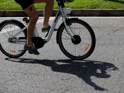 Una hombre transita la madrileña calle Alcalá con una bicicleta del servicio público Bicimad.