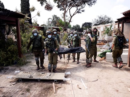 Unos soldados israelíes trasladaban el martes a una víctima de la matanza perpetrada por Hamás en el kibutz Kfar Aza.